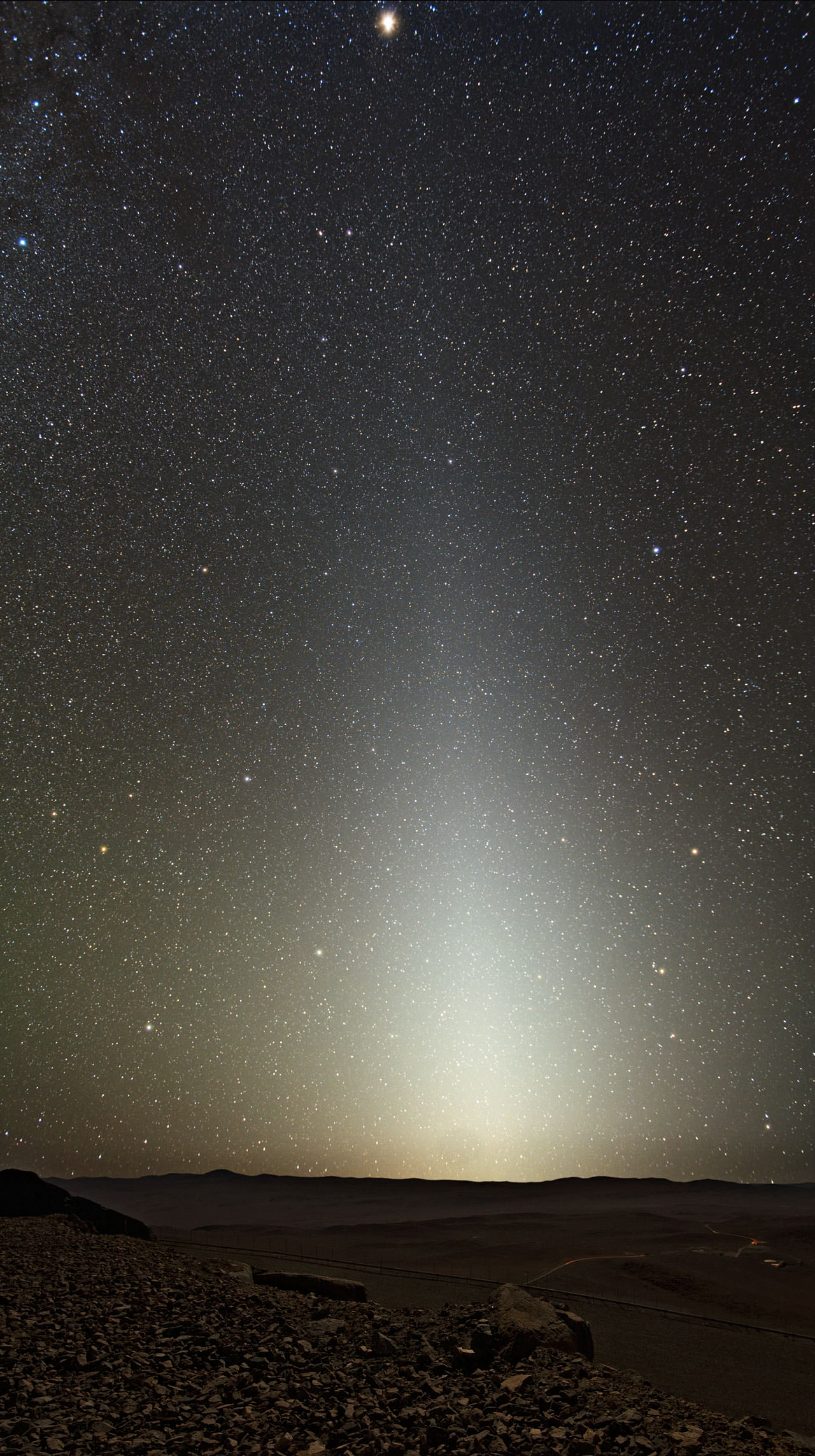 A starry sky, with a bright column due to zodiacal light, illuminates the desert landscape around Cerro Paranal, home to ESO's Very Large Telescope (VLT).
