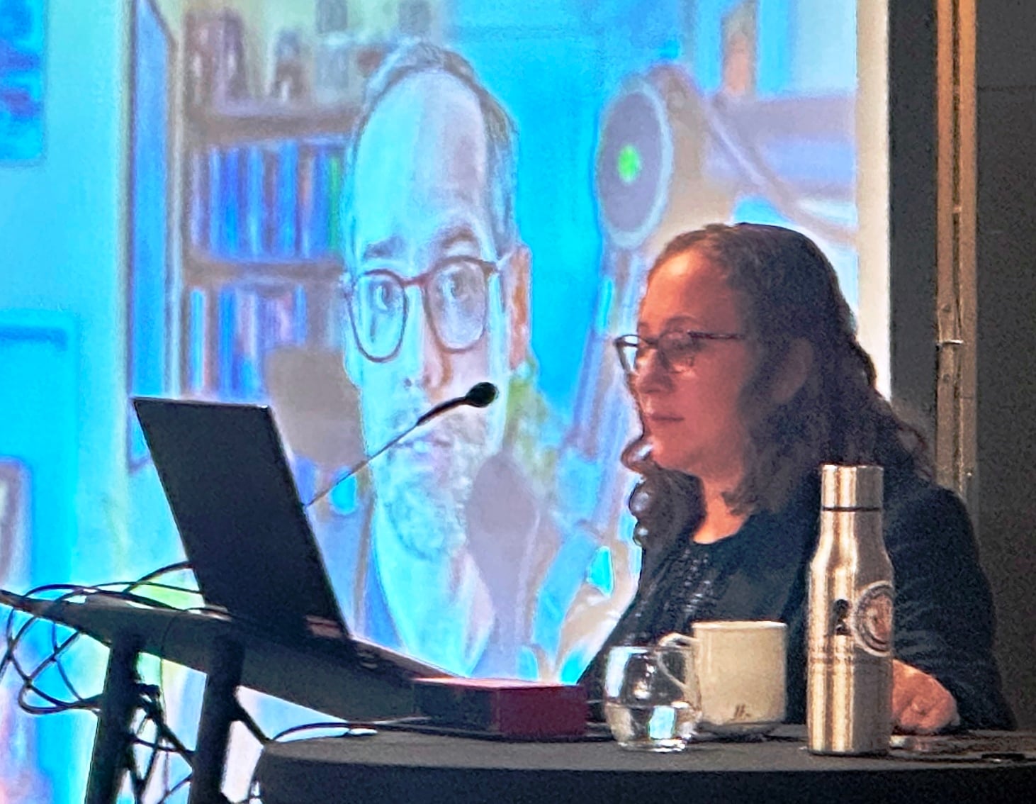 The Planetary Society’s Casey Dreier, seen on the video screen, discusses space policy with Clara Moskowitz of Scientific American at a ScienceWriters2025 session. (Photo by Alan Boyle)