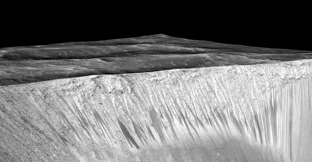 Dark narrow streaks, called "recurring slope lineae," emanate from the walls of Garni Crater on Mars. Credit: NASA