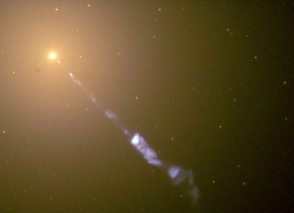 Image taken by the Hubble Space Telescope of a 5000-light-year-long jet ejected from the active galaxy M87. The blue synchrotron radiation contrasts with the yellow starlight from the host galaxy. The dots spread around the image are not individual stars, but globular star clusters. Credit: NASA/The Hubble Heritage Team (STScI/AURA) 