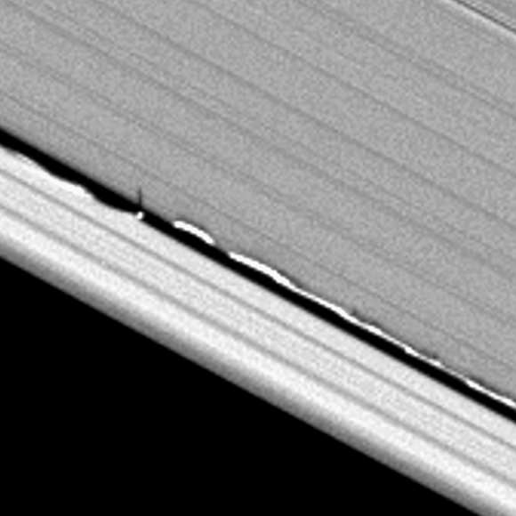 Looming vertical structures, seen here for the first time and created by Saturn's moon Daphnis, rise above the planet's otherwise flat, thin disk of rings to cast long shadows in this Cassini image.  Credit: CICLOPS