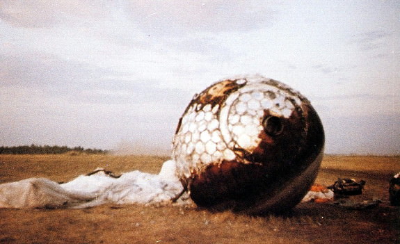 Here the re-entry capsule of the Vostok 3KA-3 (also known as Vostok 1) spacecraft (Vostok 1) is seen with charring and its parachute on the ground after landing south west of Engels, in the Saratov region of southern Russia. Credit: space.com