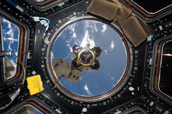 The end effector -- or grappler -- at the end of the Space Station's Canadarm 2 robotic arm is visible out the main window of the Cupola, with a view of our beautiful blue planet below. Credit: NASA.