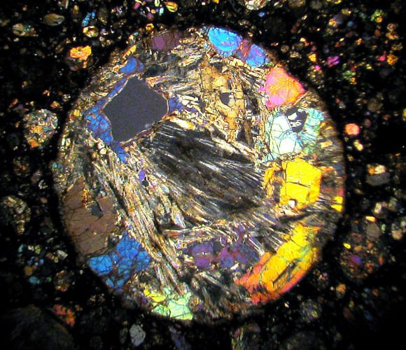 10x closeup of a very thin section through a chondrule in the meteorite NWA 4560. Crystals of olivine (bright colors) and pyroxene are visible. Credit: Bob King