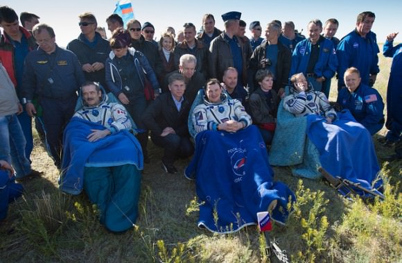 Expedition 35 Commander Chris Hadfield of the Canadian Space Agency (CSA), left, Russian Flight Engineer Roman Romanenko of the Russian Federal Space Agency (Roscosmos), center, and NASA Flight Engineer Tom Marshburn sit in chairs outside the Soyuz Capsule just minutes after they landed in a remote area outside the town of Dzhezkazgan, Kazakhstan, on Tuesday, May 14, 2013. Hadfield, Romanenko and Marshburn are returning from five months onboard the International Space Station where they served as members of the Expedition 34 and 35 crews. Photo Credit: (NASA/Carla Cioffi)