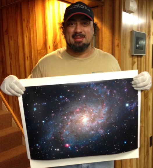 John Chumack's daughter Kayla took this picture of her Dad holding a 16x24 print of M33. Image courtesy of John Chumack. 