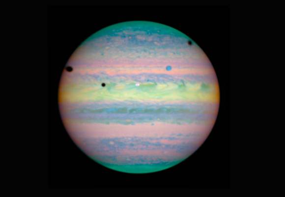 The March 28, 2004 triple transit. Shadows from left: Ganymede, Io and Callisto. You can also see the disks of Io (white dot) and Ganymede (blue dot) in this photo taken in infrared light by the Hubble Space Telescope. Credit: NASA/ESA