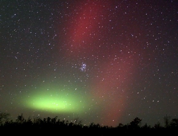 A single patch of aurora glows beneath the Pleiades star cluster at center. Beautiful red rays as seen in the time exposure were only faintly visible with the naked eye. Credit: Bob King