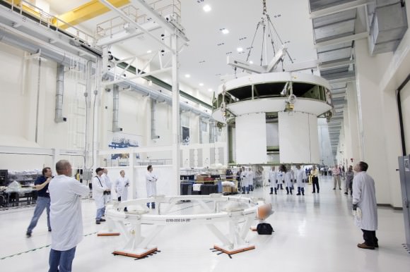 Inside the Operations and Checkout Building high bay at NASA’s Kennedy Space Center in Florida, a crane moves the service module for the Orion spacecraft toward a lift station where it will be mated to the spacecraft adapter cone. Photo credit: NASA/Jim Grossmann