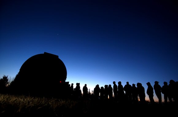 A line of visitors is cast in silhouette against the evening sky as they wait to go into the Frosty Drew Observatory. (Susannah Snowden / The Westerly Sun)