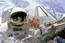 NASA astronaut Dale Gardner holds a "For Sale" sign during STS-51A in 1984, referring to two satellites captured and retrieved on that mission. Credit: NASA