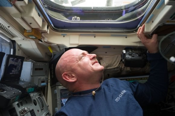 NASA astronaut Mark Kelly peers out a window during the penultimate shuttle mission, STS-134, in 2011. Around his neck is the ring of his wife, Gabrielle Giffords, who was recovering from a gunshot head wound during the mission. Credit: NASA