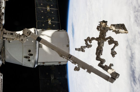 Backdropped against a cloudy portion of Earth, Canada’s Dextre robotic "handyman" and Canadarm2 dig out the trunk of SpaceX’s Dragon cargo vessel docked to the ISS after completing a task 225 miles above the home planet. Credit: NASA