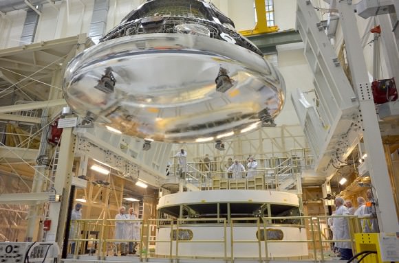 The Orion crew module for Exploration Flight Test-1 is shown in the Final Assembly and System Testing (FAST) Cell, positioned over the service module just prior to mating the two sections together. Credit:   NASA/Rad Sinyak