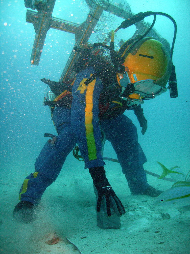 An unidentified member of NEEMO 14 bends down to pick up a rock. The crew included astronauts and non-astronauts. Credit: NASA