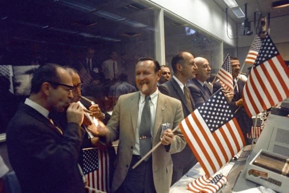 Celebrating Apollo 11.  NASA and Manned Spacecraft Center (MSC) officials joined with flight controllers to celebrate the successful conclusion of the Apollo 11 lunar landing mission in the Mission Control Center. From left foreground Dr. Maxime A. Faget, MSC Director of Engineering and Development; George S. Trimble, MSC Deputy Director; Dr. Christopher C. Kraft Jr., MSC Director fo Flight Operations; Julian Scheer (in back), Assistant Adminstrator, Office of Public Affairs, NASA HQ.; George M. Low, Manager, Apollo Spacecraft Program, MSC; Dr. Robert R. Gilruth, MSC Director; and Charles W. Mathews, Deputy Associate Administrator, Office of Manned Space Flight, NASA HQ.  Credit: NASA