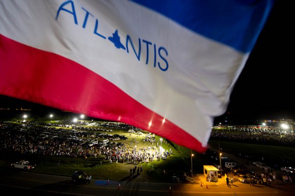 The flag of Atlantis flies from the Mobile Launcher Platform that brought Atlantis to the launch pad, May 31, 2011. Below the flag are crowds of people who attended the rollout. Credit: NASA/Bill Ingalls