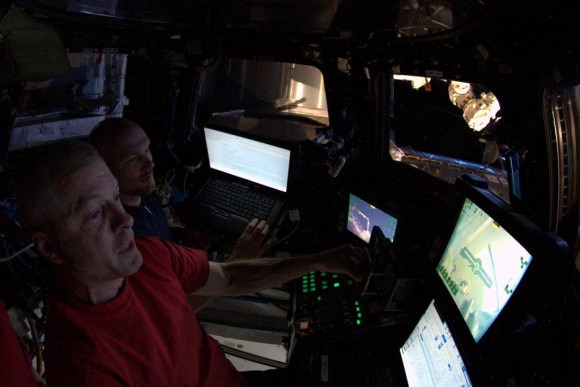 In this photo posted to Twitter by Flight Engineer Alexander Gerst, he and Commander Steve Swanson (foreground) use the robotics workstation in the International Space Station's cupola.  Image Credit: NASA 