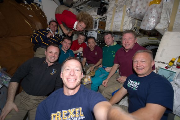 The crew members of STS-135 and Expedition 28 share a meal and a selfie on July 14, 2011, marking one of the last times a shuttle crew and International Space Station crew ate together. Credit: NASA