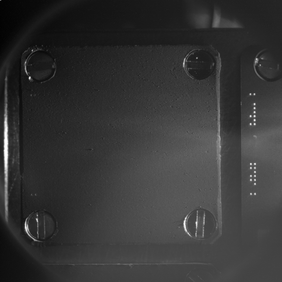 COSISCOPE image of the first target taken on 19 July 2014 (before the exposure, on 10 August, for cometary dust collection). The 1x1 cm target consists of a gold plate covered with a thin layer (30 µm) of gold nanoparticles (“gold black”). Illumination is by two LEDs, from the right side in this case. The bright dots on the vertical strip on the right side are used for target identification and for defining the coordinate system. Credits: ESA/Rosetta/MPS for COSIMA Team MPS/CSNSM/UNIBW/TUORLA/IWF/IAS/ESA/BUW/MPE/LPC2E/LCM/FMI/UTU/LISA/UOFC/vH&S