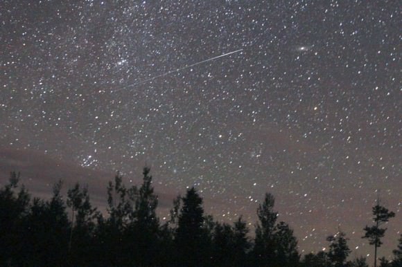 A fine Perseid flashes straight out of the radiant on August 12, 2013. The fuzzy-starry clump near the start of the trail is the Double Cluster. Credit: Bob King