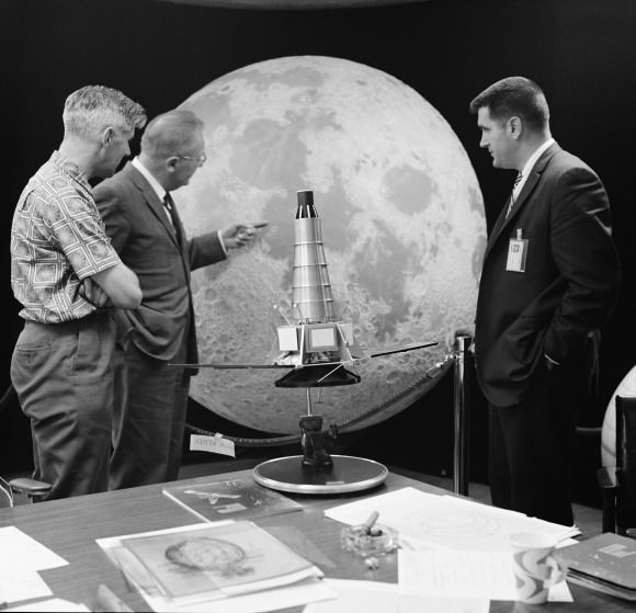 Three members of the Ranger 7 television experiment team stand near a scale model and lunar globe at NASA’s Jet Propulsion Laboratory (JPL). From left: Ewen Whitaker, Dr. Gerard Kuiper, and Ray Heacock. Kuiper was the director of the Lunar and Planetary Laboratory (LPL) at the University of Arizona. Whitaker was a research associate at LPL. Heacock was the Lunar and Planetary Instruments section chief at JPL.  Credit:  NASA/JPL-Caltech