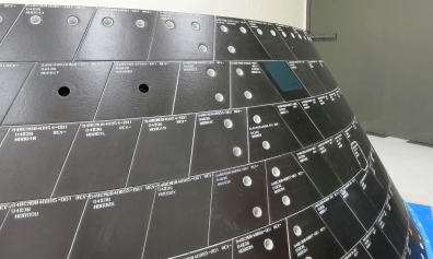 Two one-inch-wide holes have been drilled into tiles on Orion’s back shell to simulate micrometeoroid orbital debris damage.  Sensors on the vehicle will record how high temperatures climb inside the hole during Orion’s return through Earth’s atmosphere following its first flight in December.  Credit:  NASA