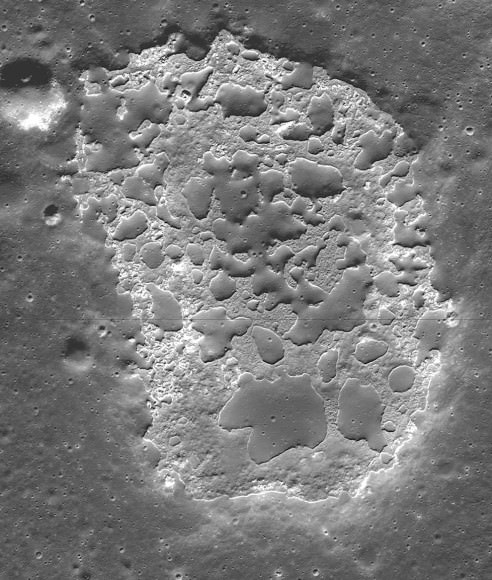 Ina Caldera sits atop a low, broad volcanic dome or shield volcano, where lavas once oozed from the moon’s crust. The darker patches in the photo are blobs of older lunar crust. As in the photo of Maskelyne, they form a series of low mounds higher than the younger, jumbled terrain around them. Credit: NASA