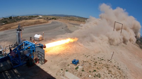 A SpaceShipTwo solid rocket motor is tested on a stand in the Mojave desert. Recent delays led Scaled Composites to swtich from a rubber-based fuel to one chemically similar to nylon. (Photo Credit: Virgin Galactic)