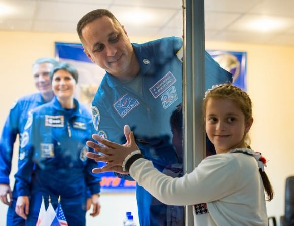 Prior to the launch of Expedition 42 in November 2014, Anton Shkaplerov (Roscosmos, center) visits with a family member (at right) through the glass at a pre-flight press conference. In the background are his crewmates, from left: Terry Virts (NASA) Samantha Cristoforetti (ESA). Credit: NASA/Aubrey Gemignani