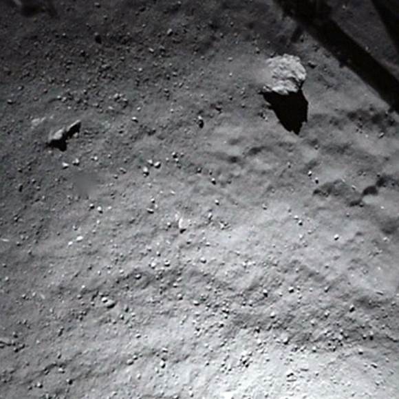 Image from the Philae lander as it approached the surface. The dust-covered boulder at upper right is about 5 meters (16.4 feet) across. The dust might have originated through vaporization of ice on the boulder itself or deposited there by dust settling from jets elsewhere.  Credit: ESA
