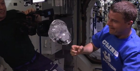 Expedition 40 commander Steve Swanson (left) and Reid Wiseman view a water bubble surrounding a video camera on the International Space Station in summer 2014. Credit: NASA/YouTube (screenshot)