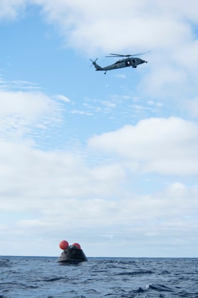 An MH-60 helicopter flies over the Orion as recovery teams move in to retrieve the spacecraft. Credit: U.S. Navy