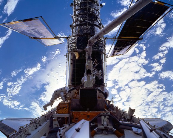 The Hubble Space Telescope during a 1999 repair mission with STS-103 crew members Mike Foale (left, for NASA) and Claude Nicollier (European Space Agency). Credit: NASA