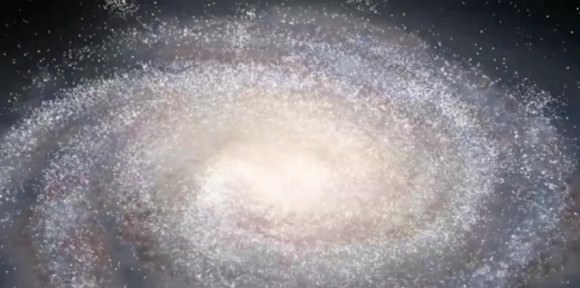 A still photo from an animated flythrough of the universe using SDSS data. This image shows our Milky Way Galaxy. The galaxy shape is an artist’s conception, and each of the small white dots is one of the hundreds of thousands of stars as seen by the SDSS. Image credit: Dana Berry / SkyWorks Digital, Inc. and Jonathan Bird (Vanderbilt University)