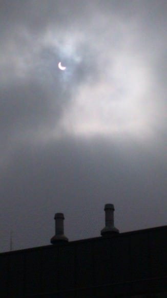 The partial eclipse peeks out from behind the clouds over the Greek Embassy . Credit and copyright: clausdm @cldm_ish