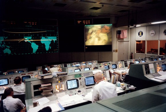 Flight Director Gene Kranz (closest to the camera) watches Fred Haise on a screen in Mission Control during a broadcast back to Earth, just 17 minutes and 42 seconds before the explosion.  Credit: NASA. 