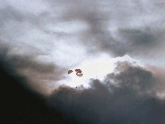 The Apollo 13 spacecraft heads toward a splashdown in the South Pacific Ocean. Note the capsule and its parachutes just visible against a gap in the dark clouds. Credit: NASA.