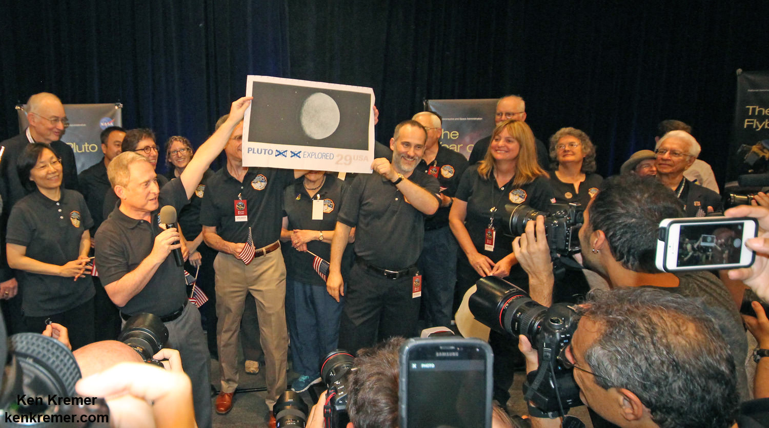 Pluto Explored at Last. The New Horizons mission team celebrates successful flyby of Pluto in the moments after closest approach at 7:49 a.m. EDT on July 14, 2015.   New Horizons Principal Investigator Alan Stern of Southwest Research Institute (SwRI), Boulder, CO., left, Johns Hopkins University Applied Physics Laboratory (APL) Director Ralph Semmel, center, and New Horizons Co-Investigator Will Grundy Lowell Observatory hold an enlarged print of an U.S. stamp with their suggested update after Pluto became the final planet in our solar system to be explored by an American space probe (crossing out the words ‘not yet’) - at the Johns Hopkins University Applied Physics Laboratory (APL) in Laurel, Maryland.  Credit: Ken Kremer/kenkremer.com 