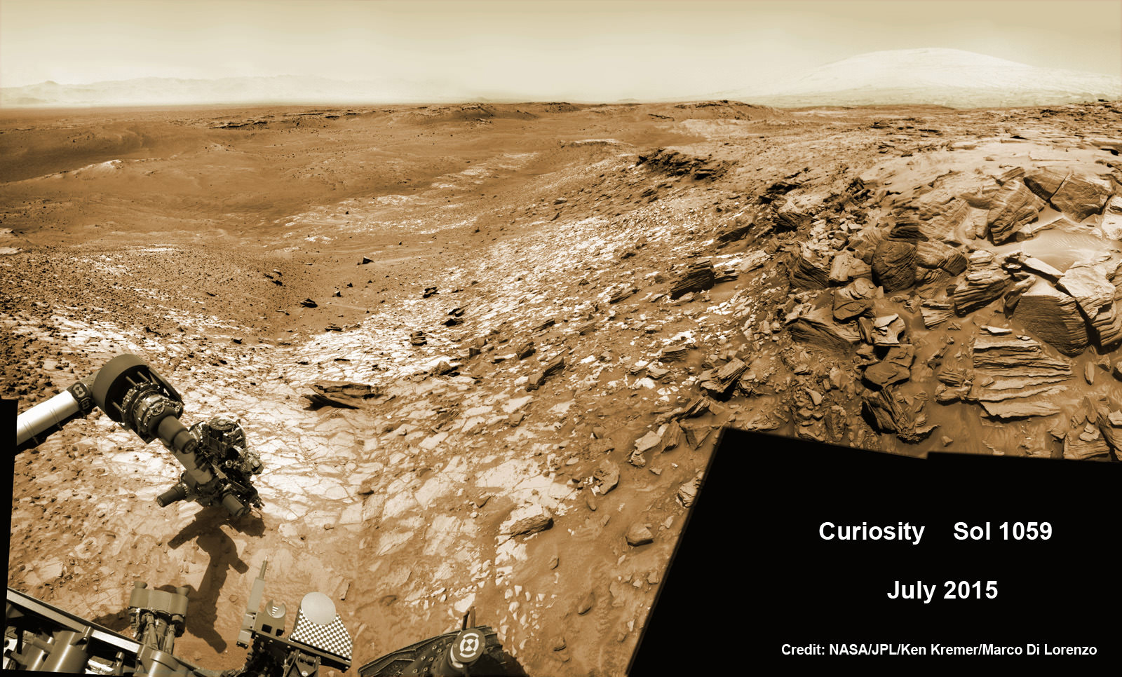 Curiosity extends robotic arm and conducts test drill at “Buckskin” rock target at bright toned “Lion” outcrop on the lower region of Mount Sharp on Mars, seen at right.   Gale Crater eroded rim seen in the distant background at left, in this composite multisol mosaic of navcam raw images taken to Sol 1059, July 30, 2015.  Navcam camera raw images stitched and colorized. Credit:  NASA/JPL-Caltech/Ken Kremer/kenkremer.com/Marco Di Lorenzo   
