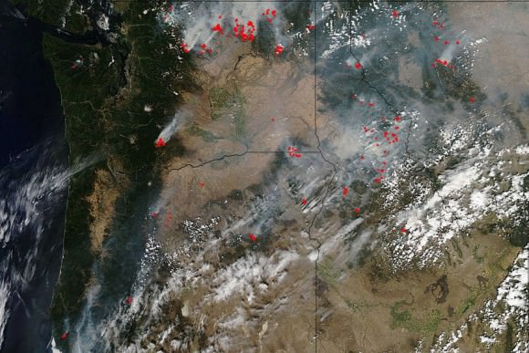 The Pacific Northwest is abundantly dotted with wildfires in Washington, Oregon, Idaho and Montana.This natural-color satellite image was made using the Aqua satellite on August 25, 2015. Actively burning areas, detected by MODIS’s thermal bands, are outlined in red. Credit: NASA image courtesy Jeff Schmaltz, MODIS Rapid Response Team