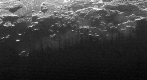 Near-Surface Haze or Fog on Pluto: In this small section of the larger crescent image of Pluto, taken by NASA’s New Horizons just 15 minutes after the spacecraft’s closest approach on July 14, 2015, the setting sun illuminates a fog or near-surface haze, which is cut by the parallel shadows of many local hills and small mountains. The image was taken from a distance of 11,000 miles (18,000 kilometers), and the width of the image is 115 miles (185 kilometers). Credits: NASA/JHUAPL/SwRI