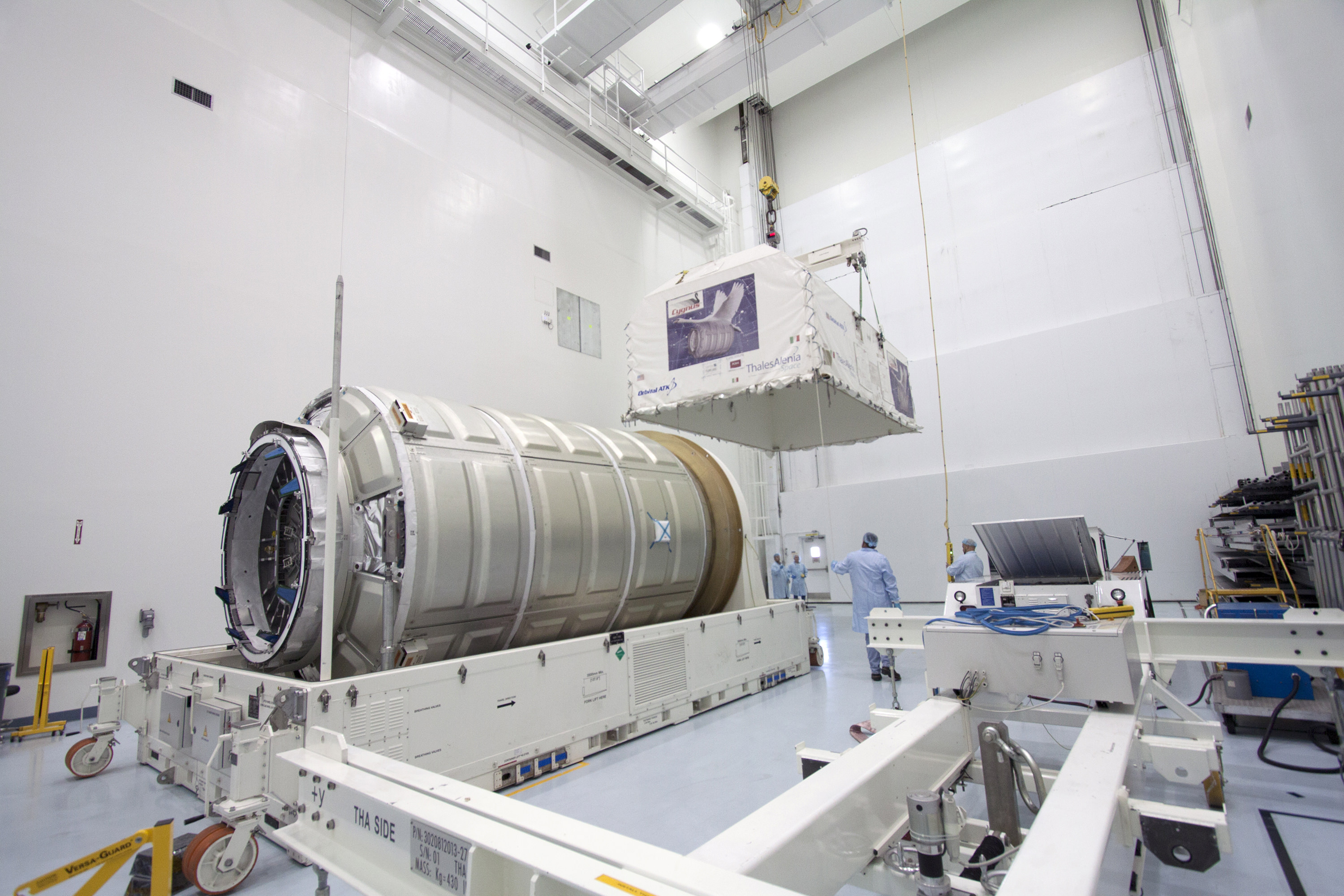 Orbital ATK Cygnus pressurized module unveiled inside Space Station Processing Facility at Kennedy Space Center in Florida as engineers remove shipping container. The module will be joined to the Cygnus service module before launch in December 2015. Photo credit: NASA/Jim Grossmann