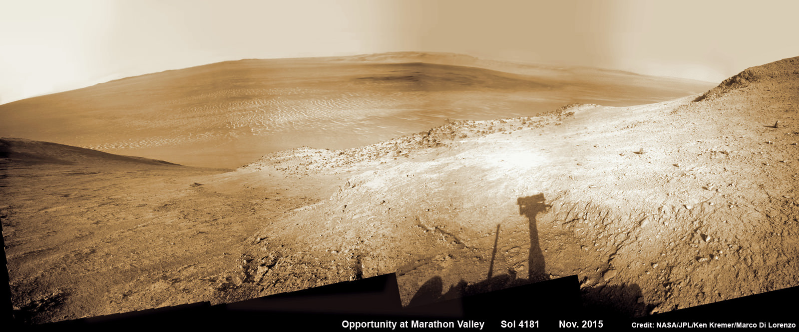 NASA’s Opportunity rover peers outwards across to the vast expense of Endeavour Crater from current location descending along steep walled Marathon Valley in early November 2015. Marathon Valley holds significant deposits of water altered clay minerals holding clues to the planets watery past.  Shadow of Pancam Mast assembly and robots deck visible at right. This navcam camera photo mosaic was assembled from images taken on Sol 4181 (Oct. 29, 2015) and colorized.  Credit: NASA/JPL/Cornell/Ken Kremer/kenkremer.com/Marco Di Lorenzo