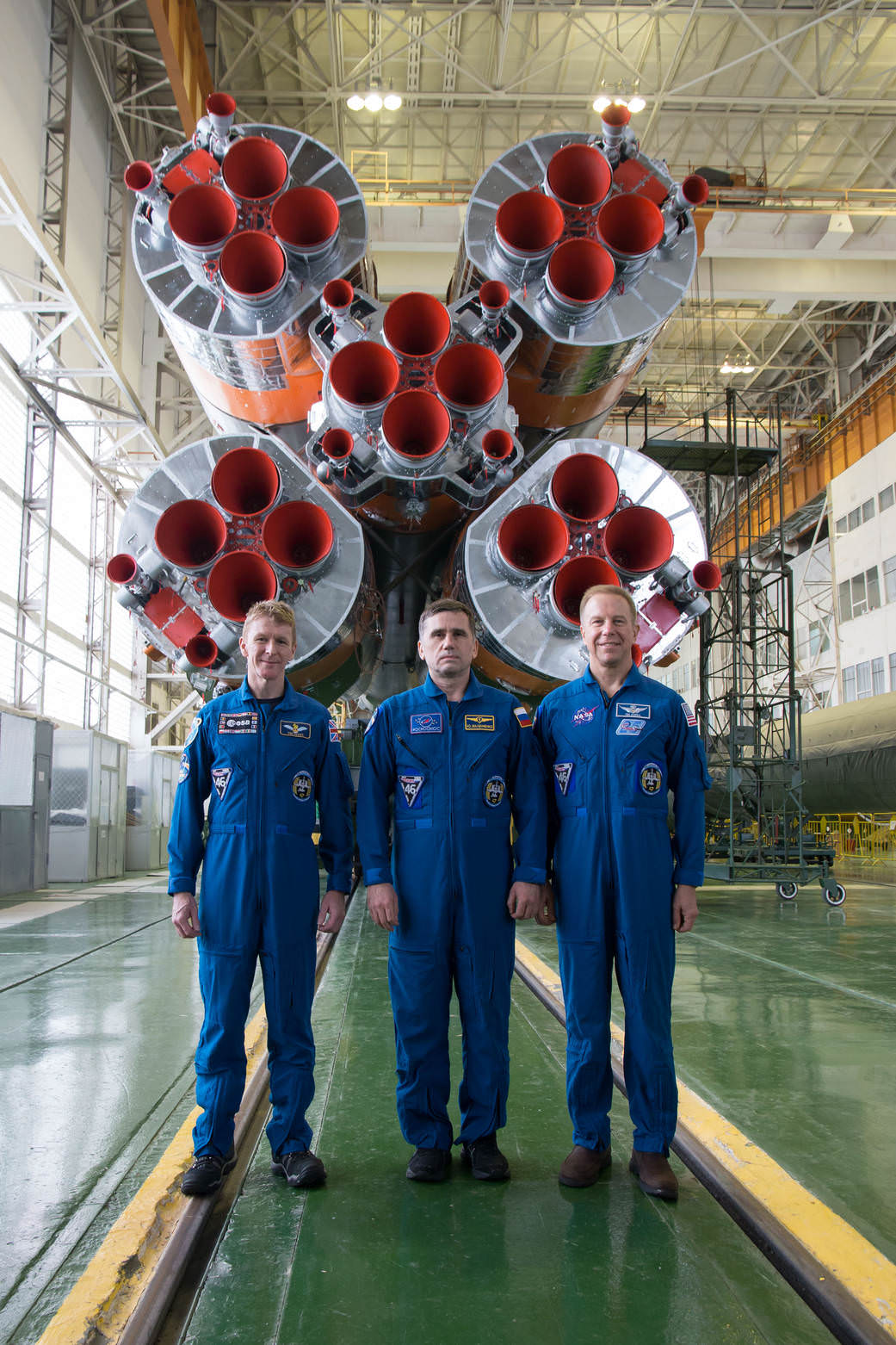 In the Integration Facility at the Baikonur Cosmodrome in Kazakhstan, Expedition 46-47 crew members Tim Peake of the European Space Agency (left), Yuri Malenchenko of the Russian Federal Space Agency (Roscosmos, center) and Tim Kopra of NASA (right) posed for pictures Dec. 10 in front of the first stage of the Soyuz booster rocket during final pre-launch training. Kopra, Peake and Malenchenko launched on  Dec. 15 on the Soyuz TMA-19M spacecraft for a six-month mission on the International Space Station. NASA/Victor Zelentsov
