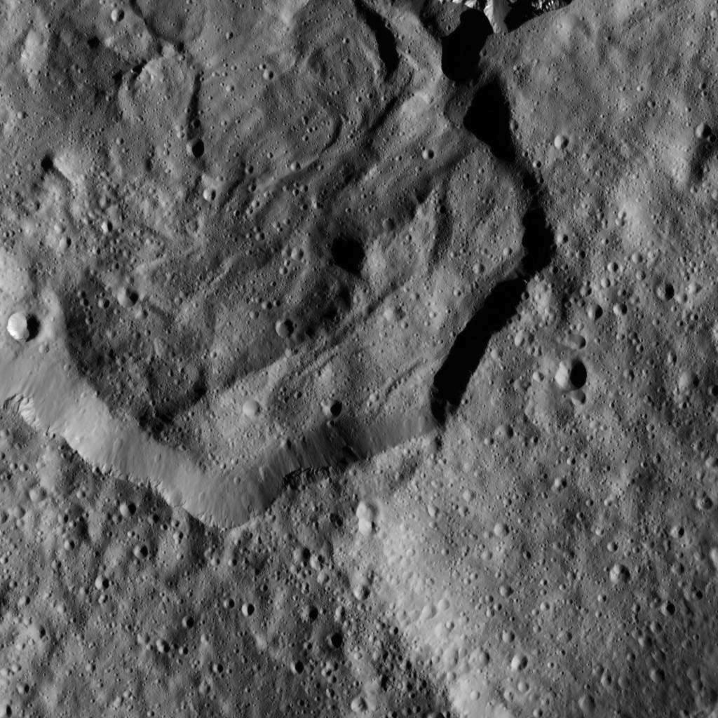 This image from NASA's Dawn spacecraft shows part of Messor Crater (25 miles or 40 kilometers, wide), located at northern mid-latitudes on Ceres. The scene shows an older crater in which a large lobe-shaped flow partly covers the northern (top) part of the crater floor. The flow is a mass of material ejected when a younger crater formed just north of the rim.  Credits: NASA/JPL-Caltech/UCLA/MPS/DLR/IDA