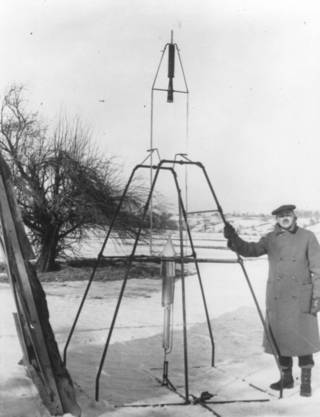 Dr. Robert H. Goddard and a liquid oxygen-gasoline rocket in the frame from which it was fired on March 16, 1926, at Auburn, Massachusetts. Image: NASA/Clark University Robert H. Goddard Archive