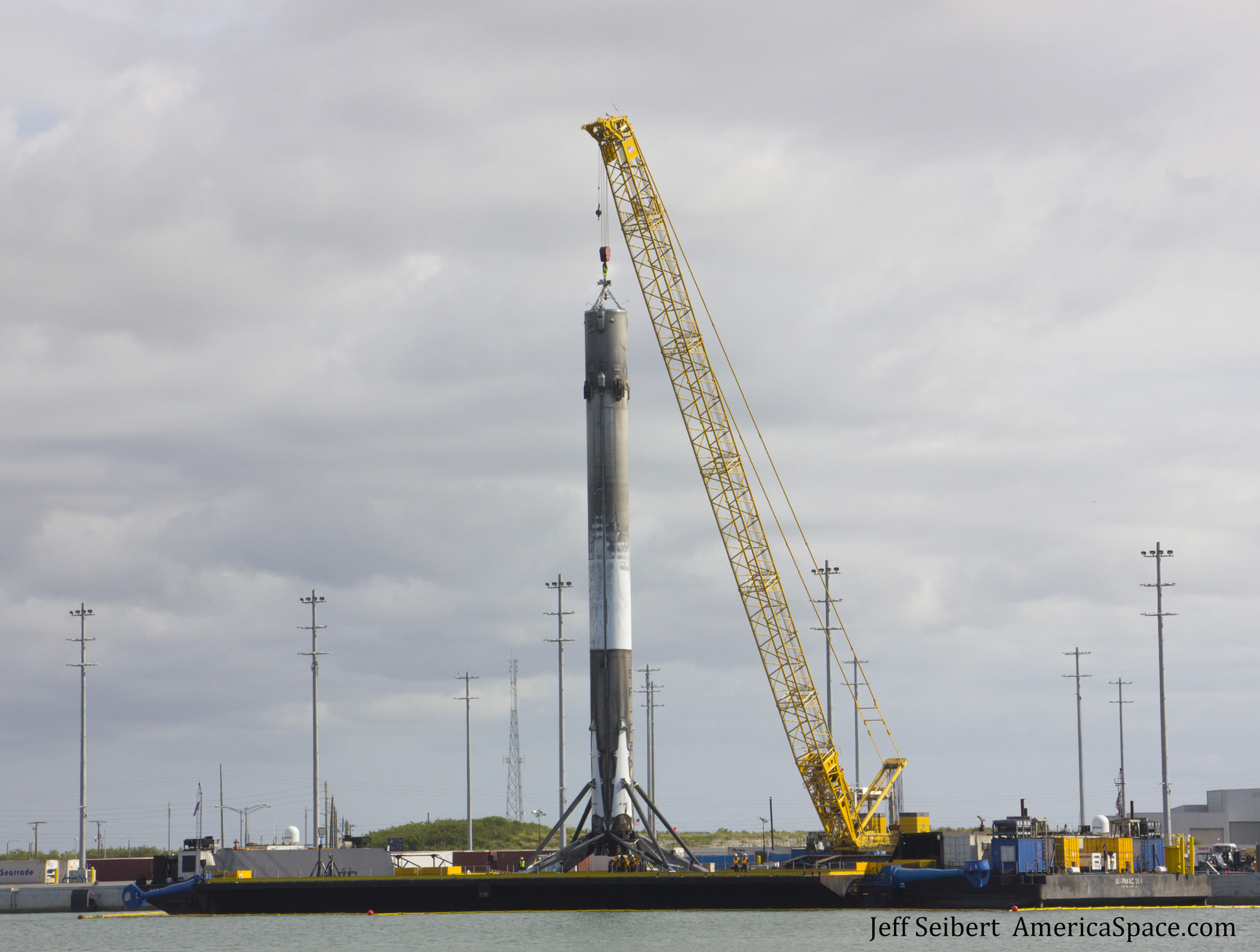 First stage booster from the SpaceX JCSAT-14 launch was moved by crane on May 11, 2016 from the drone ship OCISLY to a work pedestal on land 12 hours after arriving back in Port Canaveral, Florida.  Credit: Jeff Seibert/AmericaSpace 