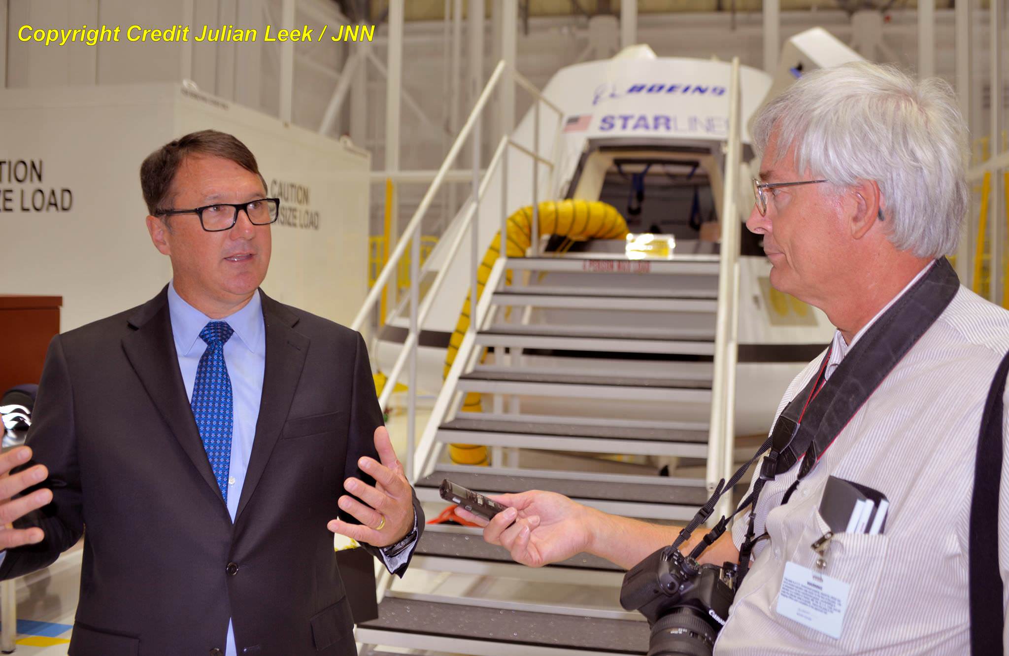 John Mulholland, vice president and program manager of Boeing Commercial Programs, and Ken Kremer, Universe Today, discuss status and assembly of 1st flightworthy Boeing Starliner by the new Starliner mockup in the Commercial Crew and Cargo Processing Facility high bay at NASA’s Kennedy Space Center in Florida.  Starliner will transport US astronauts to the ISS by 2018.  Credit: Julian Leek
