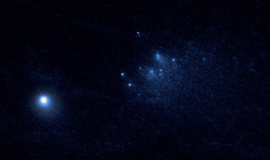 This NASA Hubble Space Telescope image reveals the ancient Comet 332P/Ikeya-Murakami disintegrating as it approaches the sun. The observations represent one of the sharpest views of an icy comet breaking apart. The comet debris consists of a cluster of building-size chunks near the center of the image. They form a 3,000-mile-long trail, larger than the width of the continental U.S. The fragments are drifting away from the comet at a leisurely pace, roughly the walking speed of an adult. The main nucleus of Comet 332P is the bright object at lower left. It measures 1,600 feet across, about the length of five football fields. Credit: NASA, ESA, and D. Jewitt (UCLA)